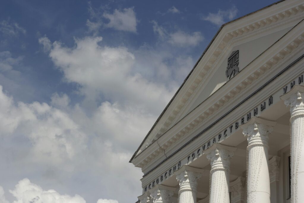 Low angle view of a classical architecture building with columns against a cloudy blue sky.